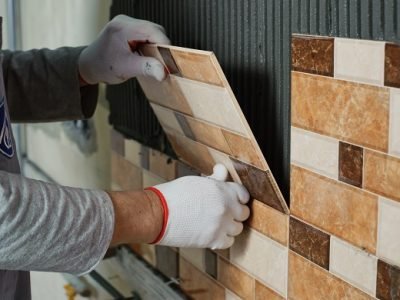 Laying Ceramic Tiles. Tiler placing ceramic wall tile in position over adhesive