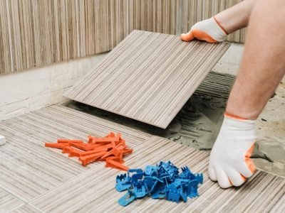 Installation of ceramic tiles. A tile's hand is puting a tile on an adhesive.
