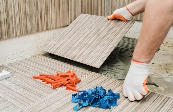 Installation of ceramic tiles. A tile's hand is puting a tile on an adhesive.